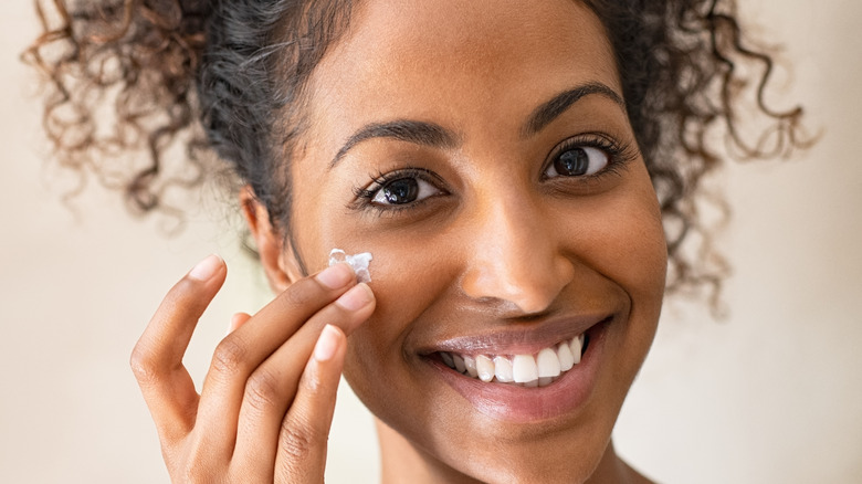 A woman applying a sunscreen to her face