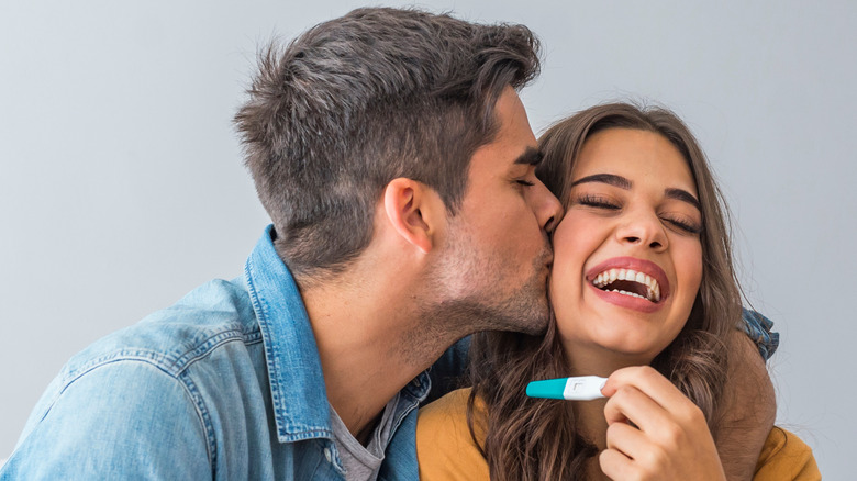 Couple kisses while holding pregnancy test