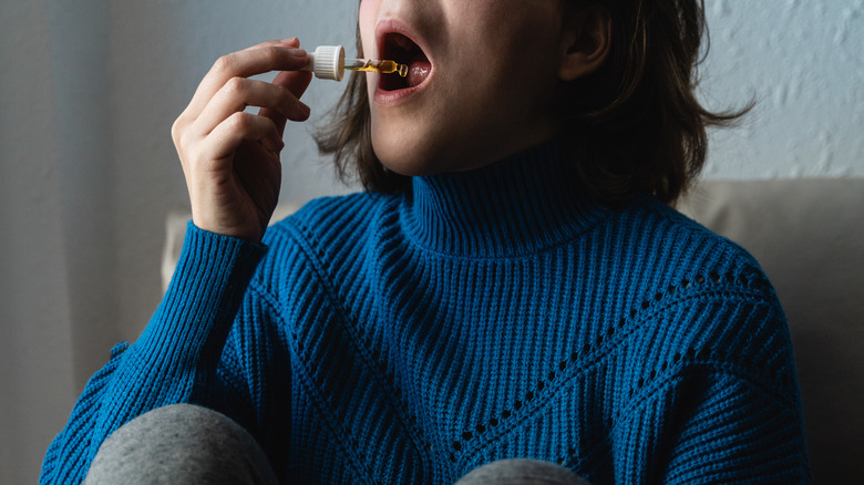 Person taking CBD oil under tongue