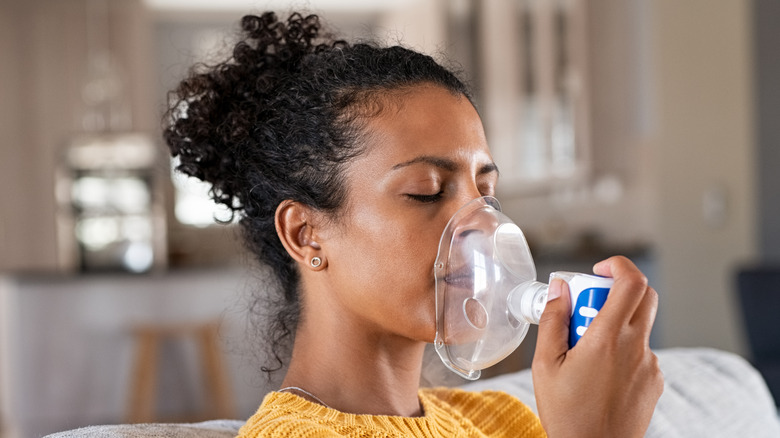 Woman with closed eyes wearing an inhaler mask over her nose and mouth