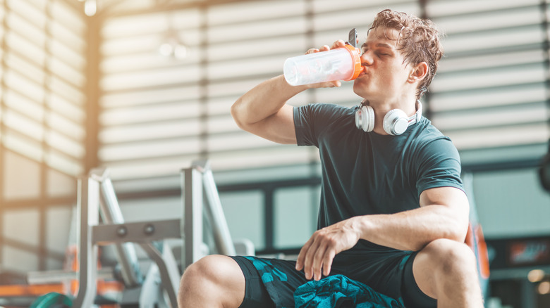 A man drinks pre-workout at the gym