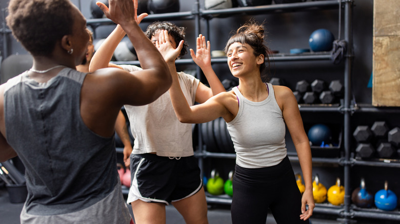 women high fiving after a workout in front of weights