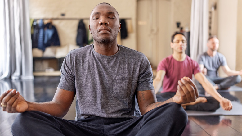 young men meditating in workout room