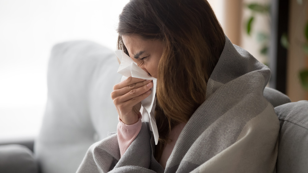 woman sneezing into a tissue