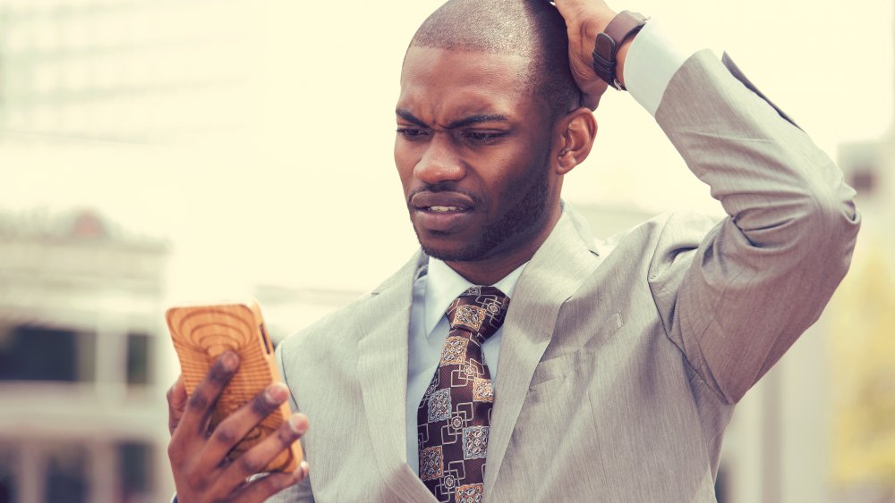 man looking stressed while staring at phone