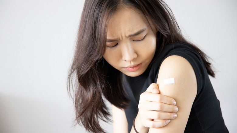 Woman holding her arm at the site of vaccine injection
