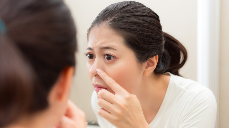 Woman looking at blackheads in mirror