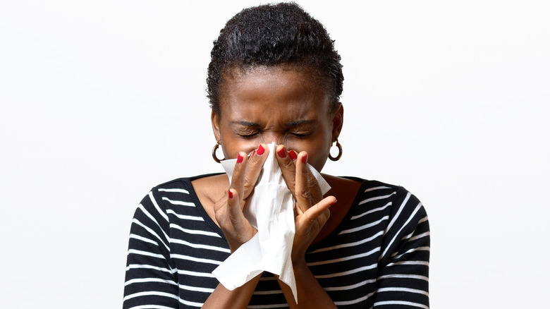 Woman blowing nose into a tissue