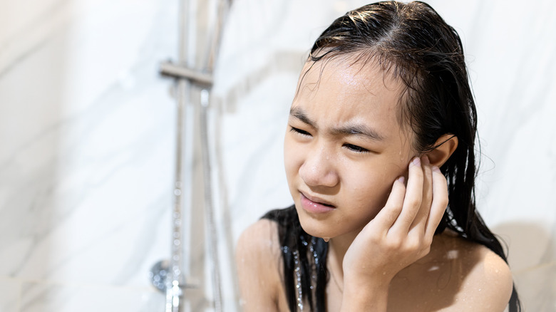 Young girl in shower holding ear in pain