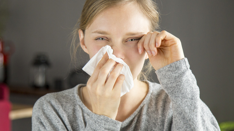 woman rubbing eye and wiping nose