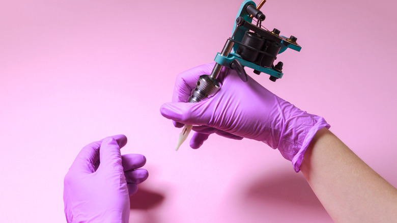 Two hands holding tattoo equipment
