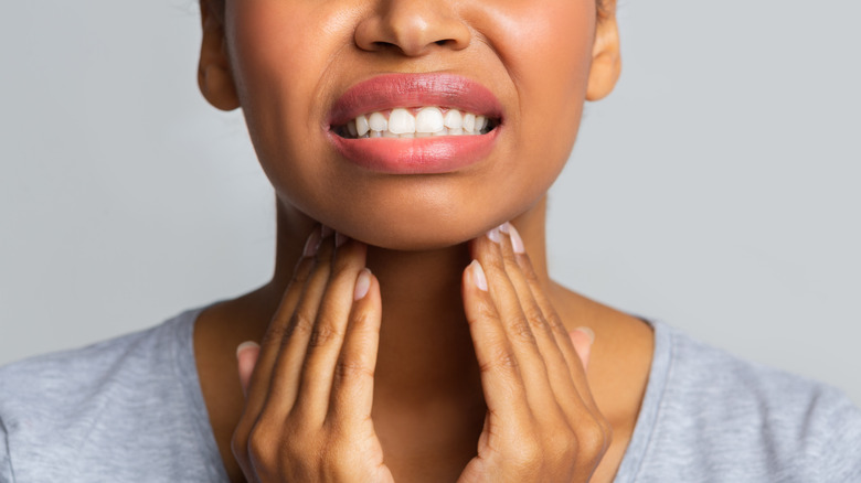 Close up of woman rubbing her inflamed tonsils