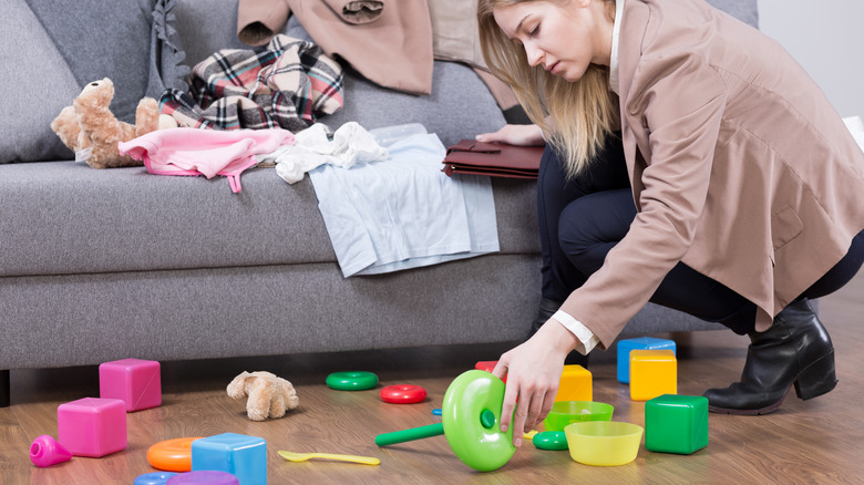 a woman is cleaning and picking up toys