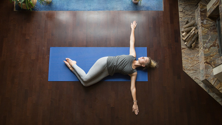 A woman performs a spinal twist yoga position