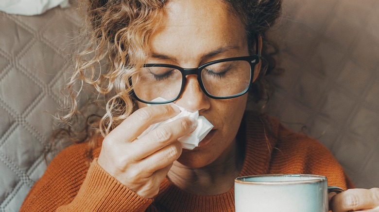 Woman holding mug and tissue