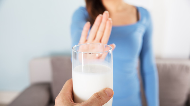 Close-up of a woman rejecting glass of milk 