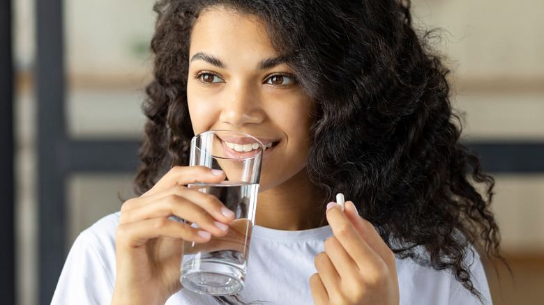 smiling black woman with supplement drinking water