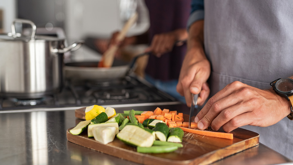 Close up of hands chopping vegetables on cutting board