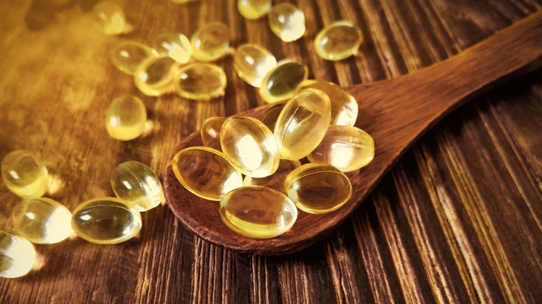 Vitamin D yellow pills on wood spoon on wooden background and soft sun light