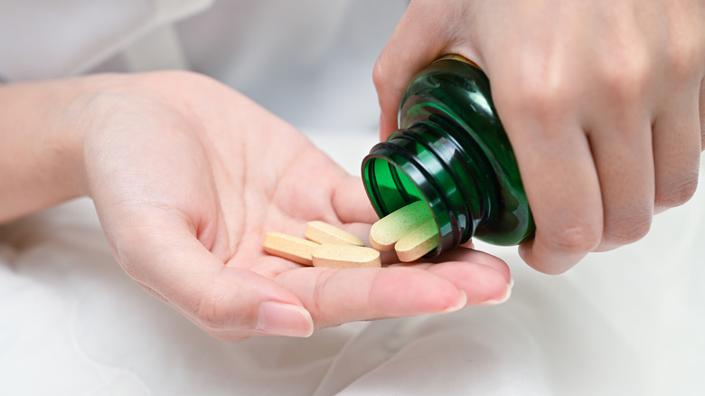 woman pouring multivitmins in hand