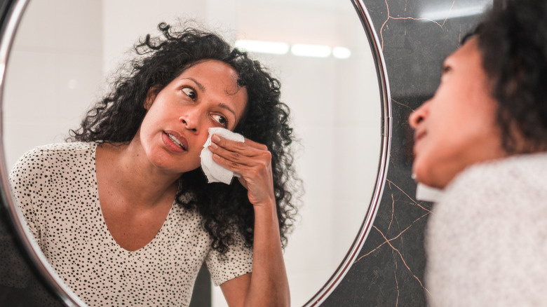 woman using a makeup wipe in mirror
