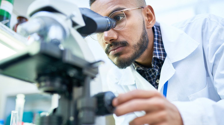 man using microscope in lab