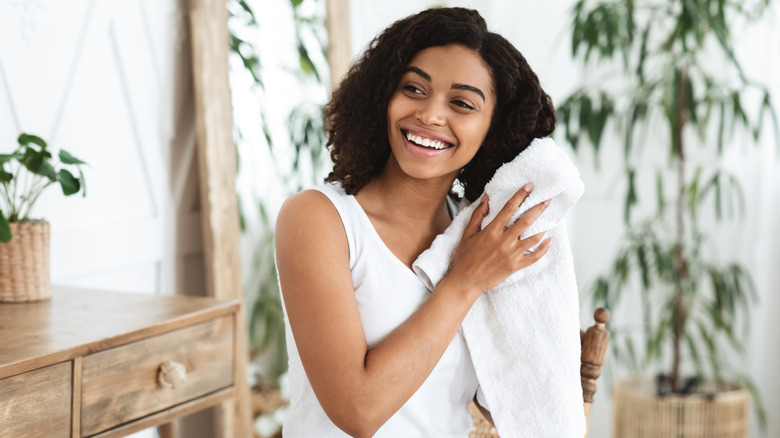 Woman smiling towel drying her hair after shower, standing in bathroom
