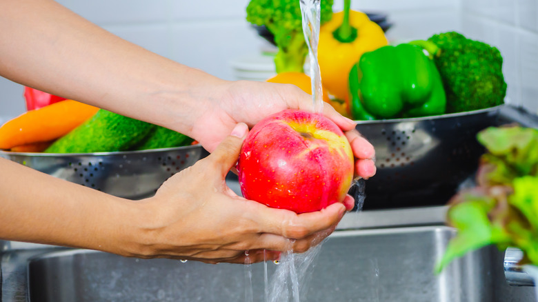 washing apple over kitchen sink