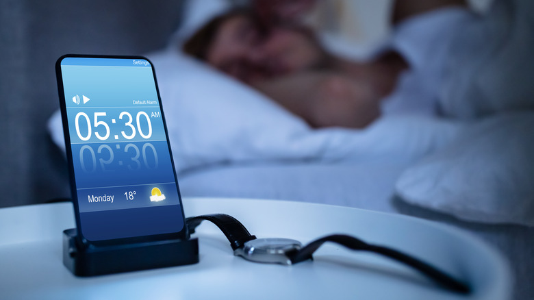 person with a phone by their nightstand