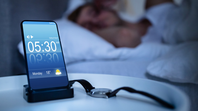 person with a phone by their nightstand