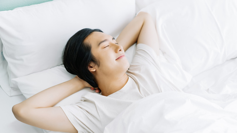 young man in bed with white pajamas happy