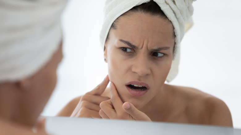 woman looking nervously in the mirror at skin