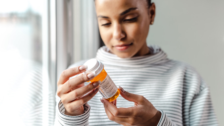 woman looking at medicine bottle 
