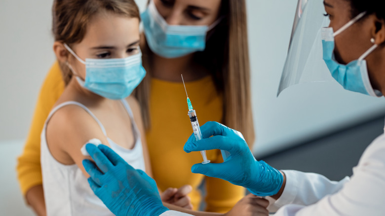 Young masked child receiving vaccine shot