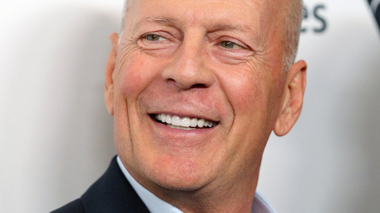 Bruce Willis close up with white background as he looks off to the left with a smile.