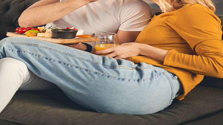 man feeding woman parmesan cheese slice at home