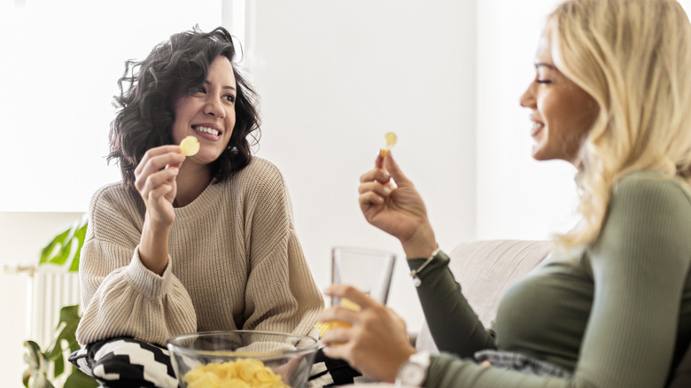 two women talking and eating potato chips
