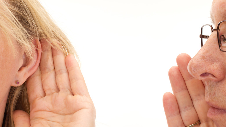 A man whispering in a woman's ear