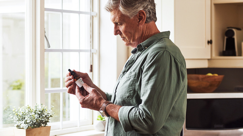 man holding a bottle of essential oil in kitchen