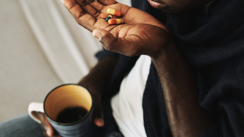 young man holding medications in his hand with coffee