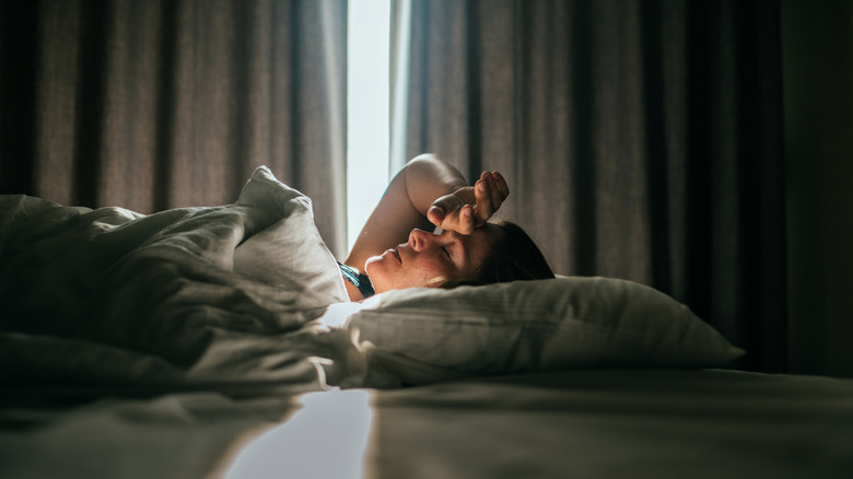 A woman waking up with her hand shielding her eyes from the sun