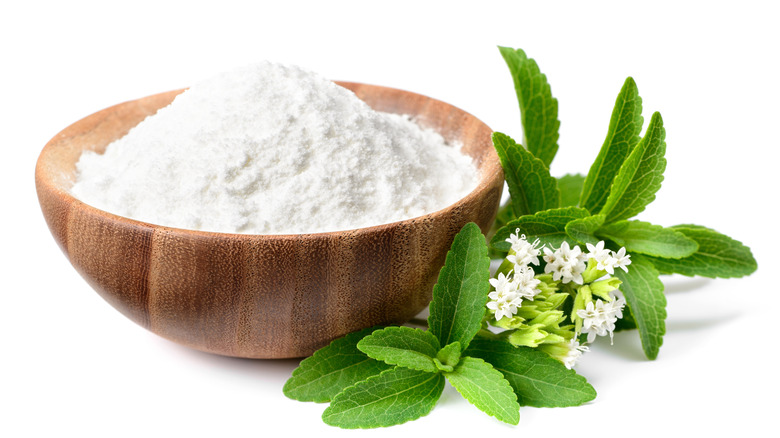 stevia leaves and stevia powder in wooden bowl