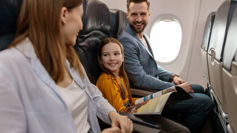 smiling girl, man, and woman on airplane