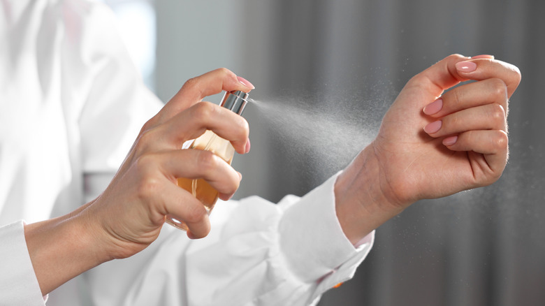 woman spraying perfume on her wrist