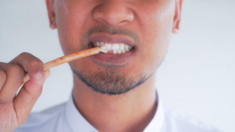 Man brushing his teeth with a chew stick