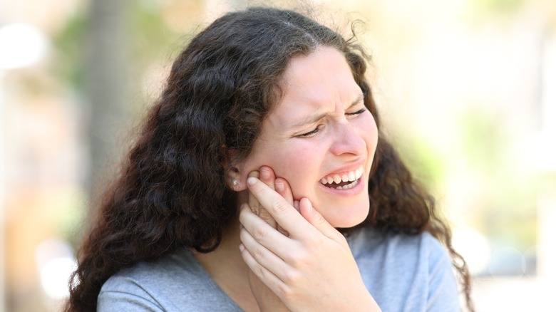 woman holding her jaw in pain