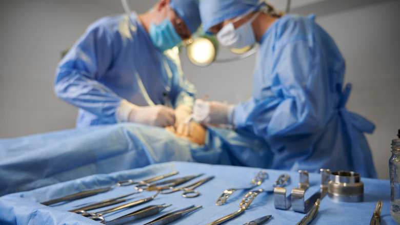 Two surgeons operating on patient's face