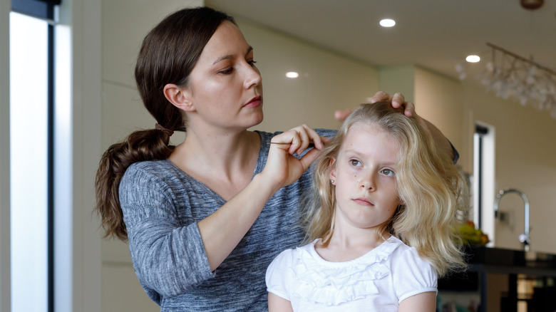 Mother checking daughter's head for lice