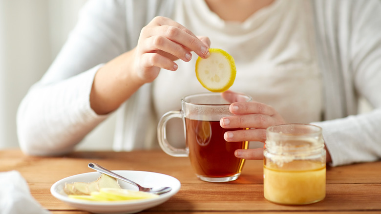 Woman preparing tea with lemon, ginger, and honey