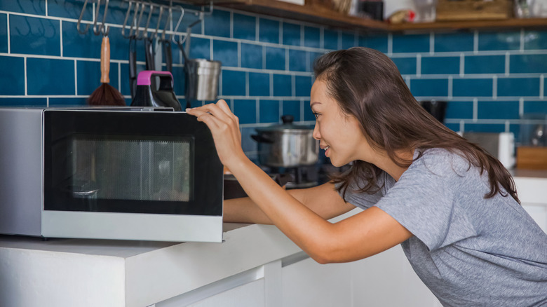 Woman looking inside microwave
